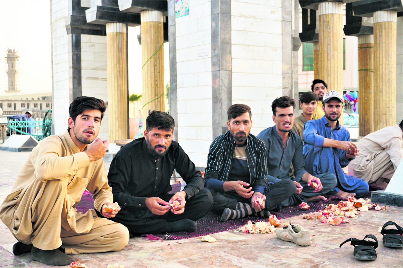 Kandahar’ın merkezinde vakit geçiren, nar yiyen bir grup erkek.